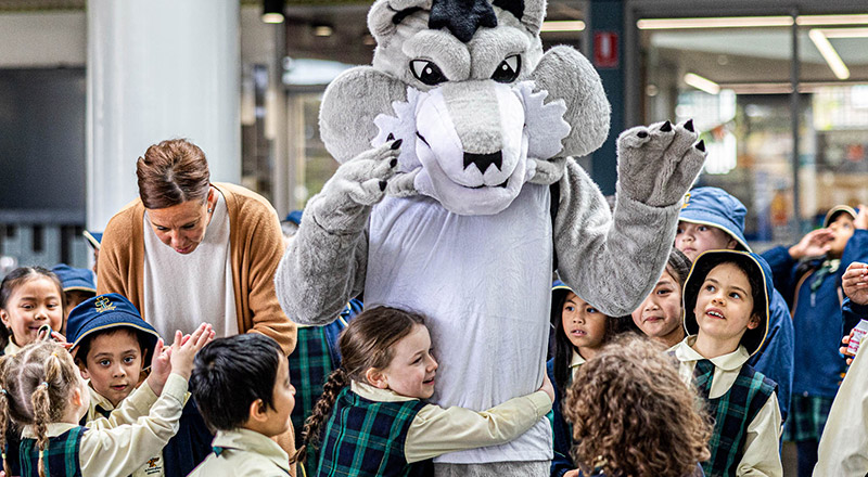 School mascot surrounded by children at St Francis of Assisi Catholic Primary School Glendenning