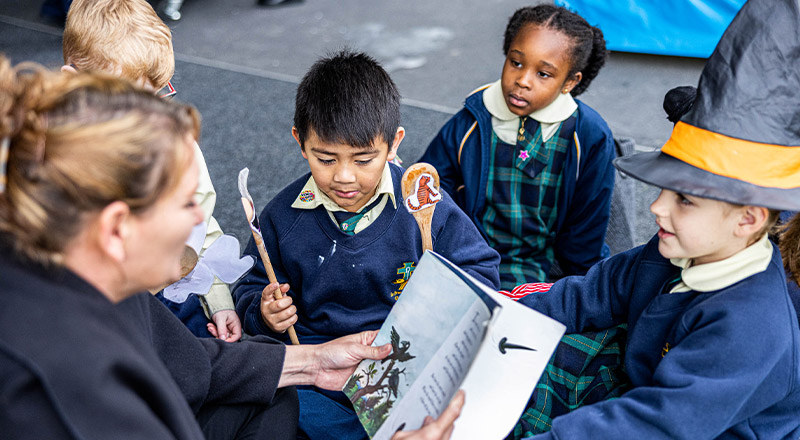 Teacher reading book to student at St Francis of Assisi Catholic Primary School Glendenning