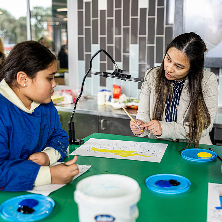 Child and teacher cooking at exterior kitchen at St Francis of Assisi Catholic Primary School Glendenning