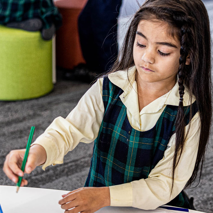 Girl writing at desk from St Francis of Assisi Catholic Primary School Glendenning