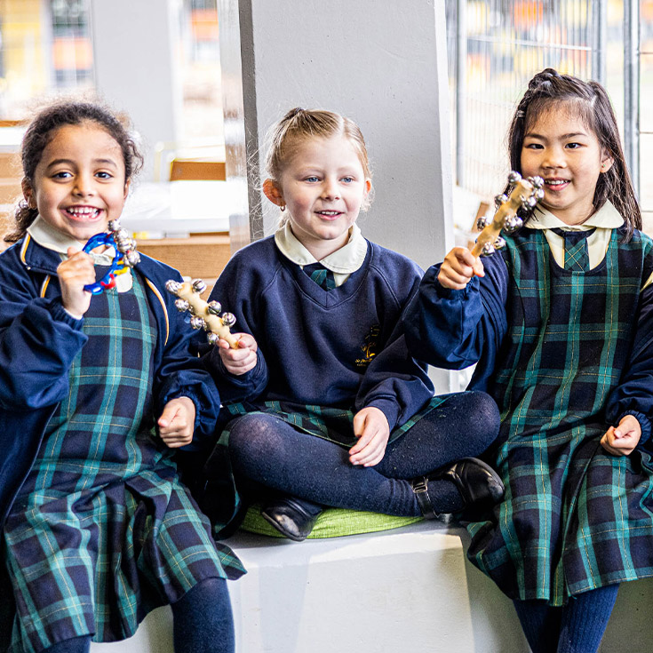 Children smiling while playing percussion at St Francis of Assisi Catholic Primary School Glendenning