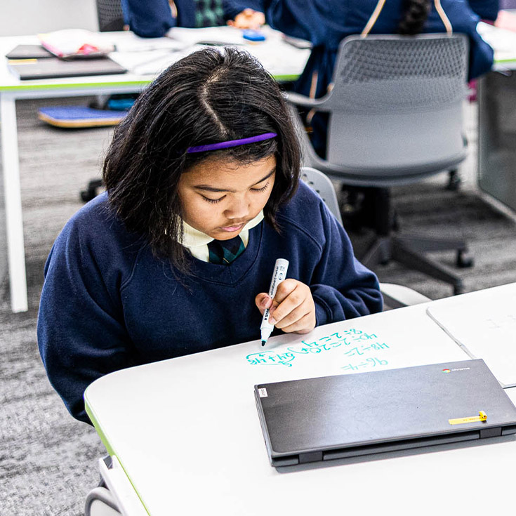 Child writing on whiteboard desk at St Francis of Assisi Catholic Primary School Glendenning