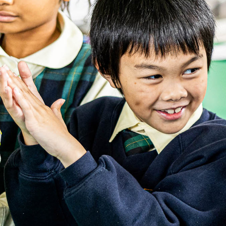 Smiling student clapping hands at St Francis of Assisi Catholic Primary School Glendenning